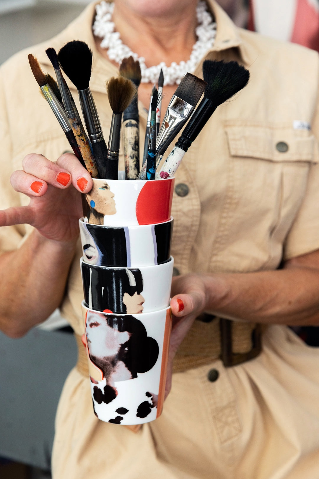 Stina Persson visar upp staplade ICONCUPS-muggar fyllda med penslar – konstnärlig inspiration i varje kopp.