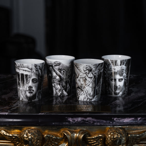 Fyra benporslinsmuggar med svartvita tatueringinspirerade motiv ur serien The Eternal Struggle av Andreas Ishak för ICONCUPS, stående på antikt bord i studiomiljö.