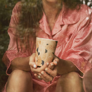 Marie Olsson Nylander håller ICONCUPS designmugg Bruno Pink i famnen – närbild på händerna.