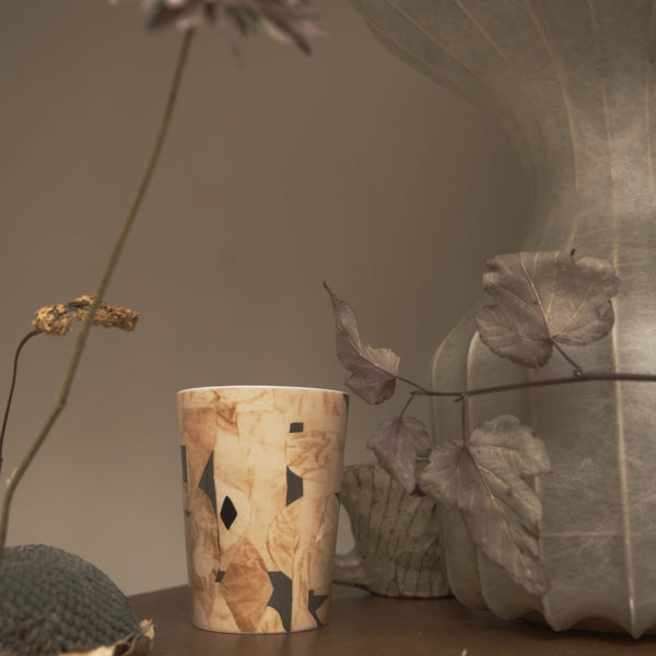 ICONCUPS designmugg – Bruno Sand av Marie Olsson Nylander – placerad på bord med växter.